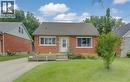 Red brick facade with stone accents, shingled roof, white-framed windows, and manicured front lawn - 104 Mausser Avenue, Kitchener, ON 