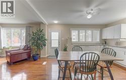 Wood-finish flooring throughout, white kitchen cabinetry with granite-style countertops, and multiple large windows for abundant natural light - 