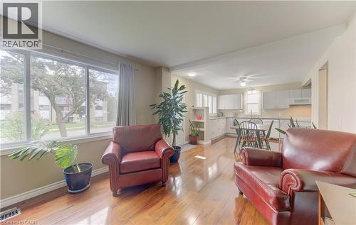 Expansive front windows, wood-finish flooring, white kitchen cabinetry, recessed lighting, and a ceiling-mounted light fixture - 104 Mausser Avenue, Kitchener, ON 