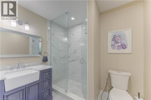Bathroom featuring a glass-enclosed shower, a vanity with a farmhouse sink, stone-finish countertops, and a mounted mirror - 104 Mausser Avenue, Kitchener, ON 