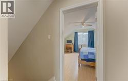 Vaulted ceiling room with wood-finish flooring, a window with curtains, and a ceiling fan - 