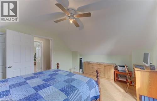 Angled ceiling architecture, light-colored walls, wood-finish flooring, ceiling fan with integrated lighting, and white paneled doors - 104 Mausser Avenue, Kitchener, ON 