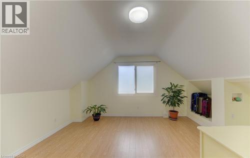 Attic space featuring sloped ceilings, wood-finish flooring, a flush-mount ceiling light, and a built-in storage alcove - 104 Mausser Avenue, Kitchener, ON 