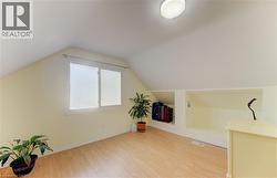 Sloped ceilings, wood-finish flooring, a double window, built-in recessed shelving, and a flush-mount ceiling light - 