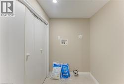 Laundry area with light-toned walls, tile flooring, and integrated utility connections - 