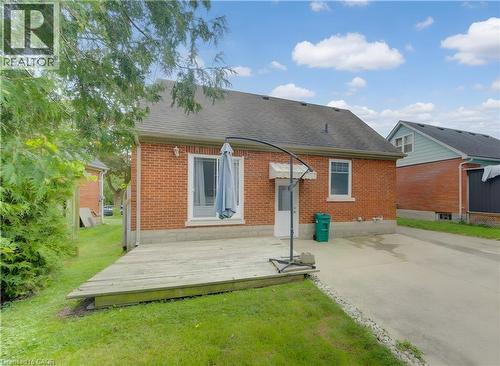 Brick exterior with a gabled roof, featuring a wooden deck, sliding glass door, and a paved driveway - 104 Mausser Avenue, Kitchener, ON 