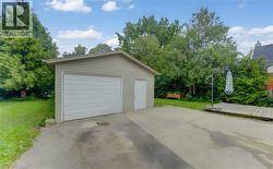 Detached garage with a single overhead door and separate entry door, concrete driveway, and wooden deck - 