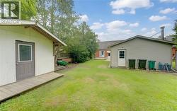 Expansive grass lawn with two detached outbuildings featuring exterior doors - 