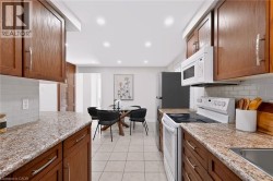 Kitchen featuring wood cabinetry, light-toned countertops, white subway tile backsplash, and recessed lighting - 