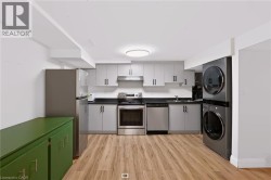 Contemporary kitchen featuring wood-finish flooring, gray cabinetry, dark countertops, and stainless steel appliances - 
