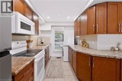 Galley kitchen featuring wood-finish cabinetry, light-toned countertops, and a tile backsplash - 
