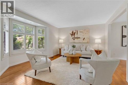 Hardwood-style flooring, bay window with plantation shutters, broadloom area rug, white wall paint, and recessed ceiling - 7 Underhill Crescent, Kitchener, ON 