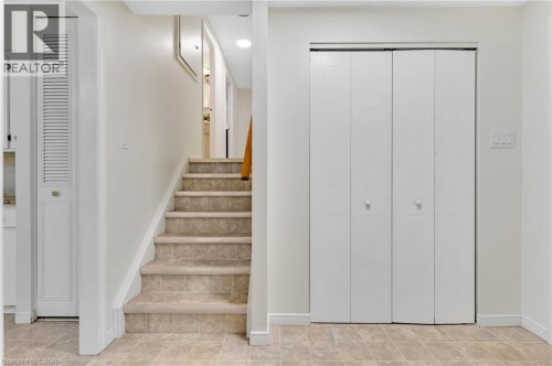 Ceramic tile flooring, carpeted stairs, bi-fold closet doors, and a louvered door - 7 Underhill Crescent, Kitchener, ON 