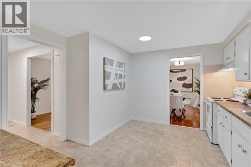 Kitchen featuring tile flooring, white cabinetry, integrated range hood, and a built-in electric range - 7 Underhill Crescent, Kitchener, ON 