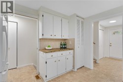 White cabinetry with gold-tone hardware, tile backsplash, and composite countertop - 