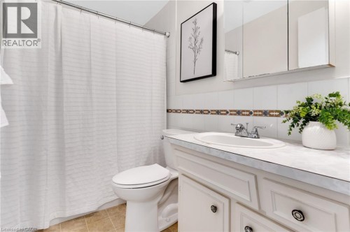 White tile backsplash with decorative accent, single vanity with integrated sink, chrome faucet, and mirrored medicine cabinet - 7 Underhill Crescent, Kitchener, ON 