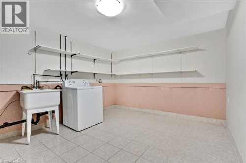 Utility room with a white utility sink, white tiled flooring, and adjustable wall-mounted shelving - 7 Underhill Crescent, Kitchener, ON 