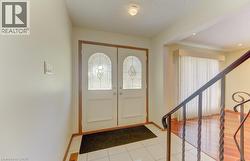 Double entry doors with decorative leaded glass inserts, tile flooring, and a wrought iron railing - 