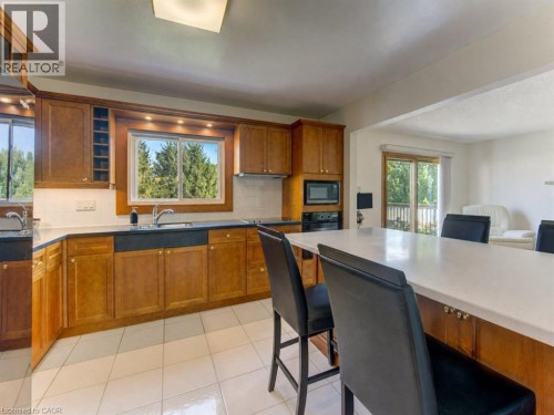 Kitchen featuring wood cabinetry, white tile flooring, integrated appliances, and a central island with seating - 238 Mcgarry Drive, Kitchener, ON 