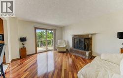 Hardwood flooring, brick fireplace with stone hearth and mantel, and a sliding glass door to a private deck - 