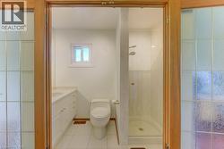 Bathroom with tile flooring, white vanity with dual sinks, and a glass-enclosed shower - 