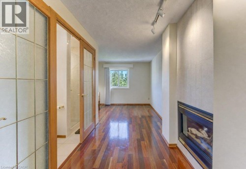 Wood-finish flooring, recessed fireplace, track lighting, frosted glass doors with wood framing, and a window with a white frame - 238 Mcgarry Drive, Kitchener, ON 