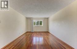 Hardwood-style flooring with a natural finish, white painted walls, and a window with a sheer curtain - 