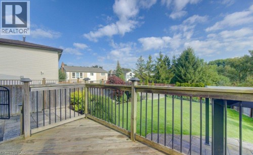 Wood-finish deck with black spindle railing, stone paver patio, and grass lawn - 238 Mcgarry Drive, Kitchener, ON 