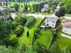 Expansive backyard featuring a manicured lawn, established landscaping, and a fenced perimeter - 