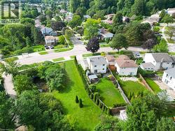 Expansive green space with mature trees, established residential streetscape, and a water feature - 