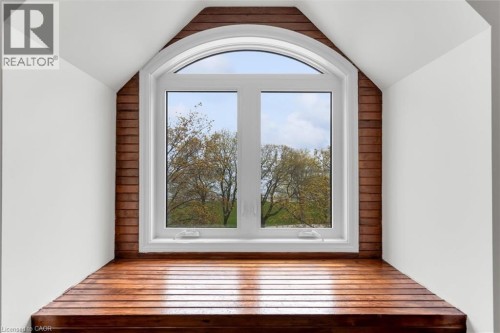 Arched window with white framing and sills, complemented by wood-finish wall paneling and a built-in wood-finish window seat - 1389 Lakeshore Road, Burlington, ON 