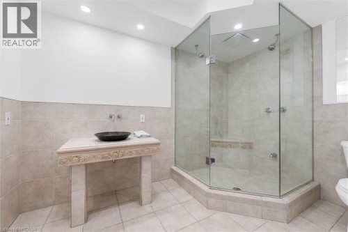 Glass-enclosed shower with a built-in bench, dual shower heads, and recessed lighting - 1389 Lakeshore Road, Burlington, ON 