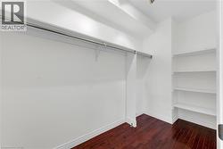 Walk-in closet featuring wood-finish flooring, built-in shelving, and a hanging clothes rod - 