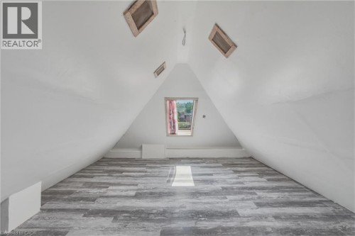 Attic space with sloped walls, wood-finish flooring, and a central window opening - 42 Nightingale Street, Hamilton, ON 
