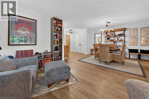 Open-concept living area featuring wood-finish flooring, built-in shelving, a chandelier, and double panel doors - 1237 North Shore Boulevard Unit# 405, Burlington, ON 