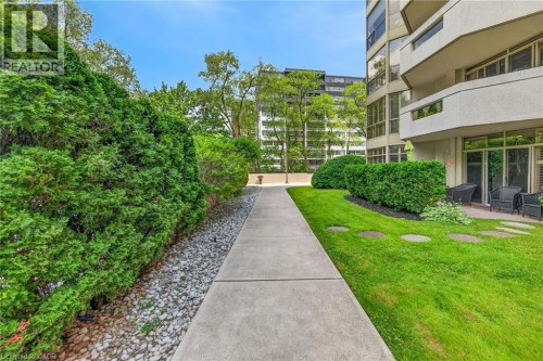 Concrete pathway bordered by manicured hedges and a gravel bed - 1237 North Shore Boulevard Unit# 405, Burlington, ON 