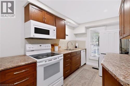 Warm wood cabinetry complemented by granite-finish countertops and a tiled backsplash - 95 Underhill Crescent, Kitchener, ON 