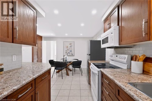 Kitchen featuring wood cabinetry, light-toned countertops, white subway tile backsplash, and recessed lighting - 95 Underhill Crescent, Kitchener, ON 