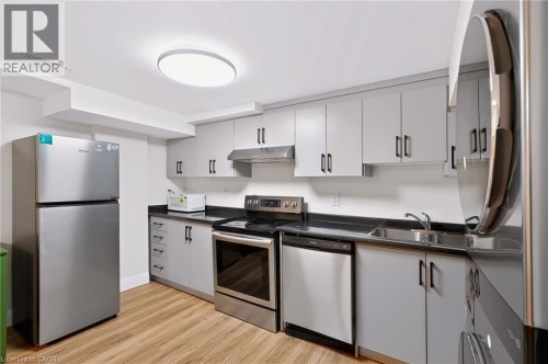 Kitchen featuring stainless steel appliances, wood-finish flooring, dark countertops, and light-toned cabinetry with dark hardware - 95 Underhill Crescent, Kitchener, ON 