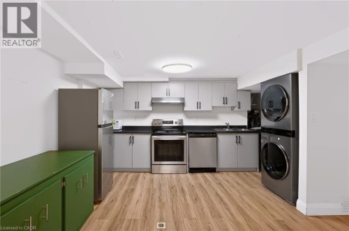 Contemporary kitchen featuring wood-finish flooring, gray cabinetry, dark countertops, and stainless steel appliances - 95 Underhill Crescent, Kitchener, ON 