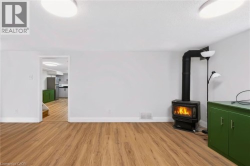 Wood-finish flooring throughout, featuring a freestanding black wood-burning stove with a visible flame - 95 Underhill Crescent, Kitchener, ON 