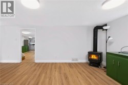 Wood-finish flooring throughout, featuring a freestanding black wood-burning stove with a visible flame - 