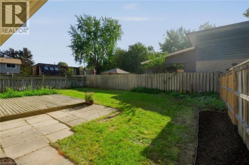Expansive grass yard with a wood-plank deck, concrete paver patio, and full-height privacy fencing - 95 Underhill Crescent, Kitchener, ON 