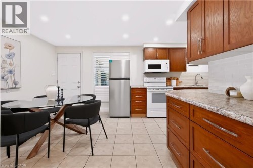 Kitchen featuring wood cabinetry, white subway tile backsplash, and light-toned tile flooring - 95 Underhill Crescent, Kitchener, ON 