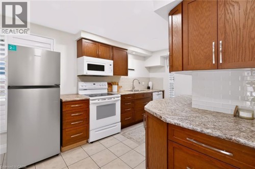 Kitchen featuring wood cabinetry, light-toned countertops, tile flooring, white subway tile backsplash, and stainless steel appliances - 95 Underhill Crescent, Kitchener, ON 