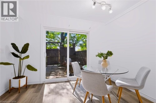 Wood-finish flooring, white walls, and a sliding glass door providing access to an outdoor patio with a privacy fence - 121 University Avenue E Unit# 102, Waterloo, ON 