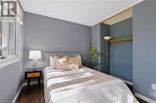 Recessed open closet with golden-finish rod, bright window with blinds, wood-finish flooring, and light blue wall paint - 121 University Avenue E Unit# 102, Waterloo, ON 