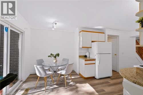 Compact kitchen area with white cabinetry, a white refrigerator, and granite-finish countertops - 121 University Avenue E Unit# 102, Waterloo, ON 
