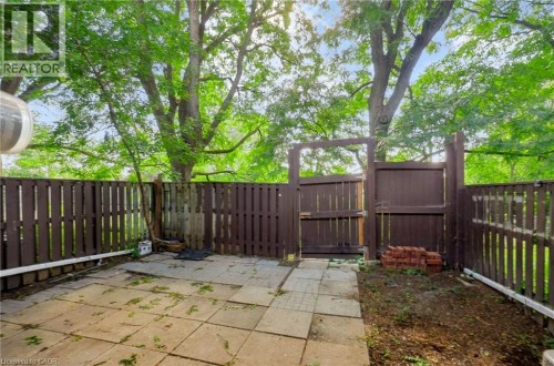 Paved patio area with a privacy fence and a wooden gate - 121 University Avenue E Unit# 102, Waterloo, ON 