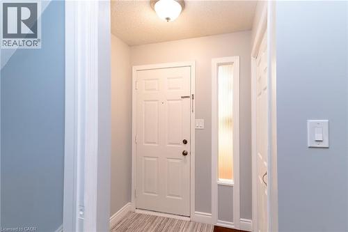 Entryway featuring a panel door, frosted vertical window, and wood-finish flooring - 543 Drummerhill Crescent, Waterloo, ON 